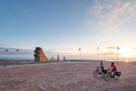 cyclistes devant un monument commémoratif à Omaha Beach